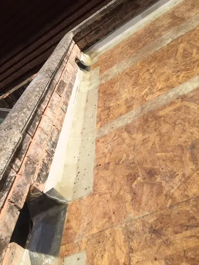 Lead soaker dressed into a gable end where the tiles have been stripped back to the boarding