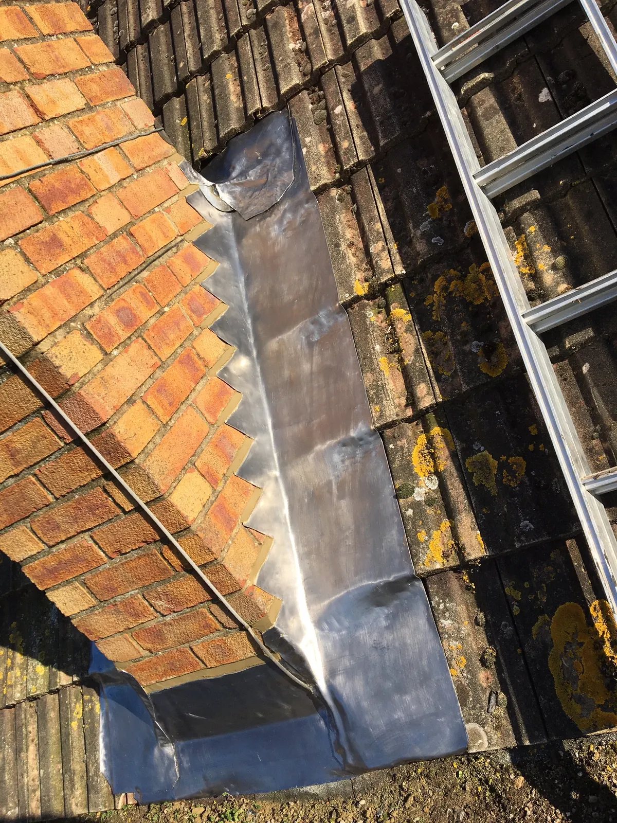 Lead flashing worked into brickwork above a tiled roof