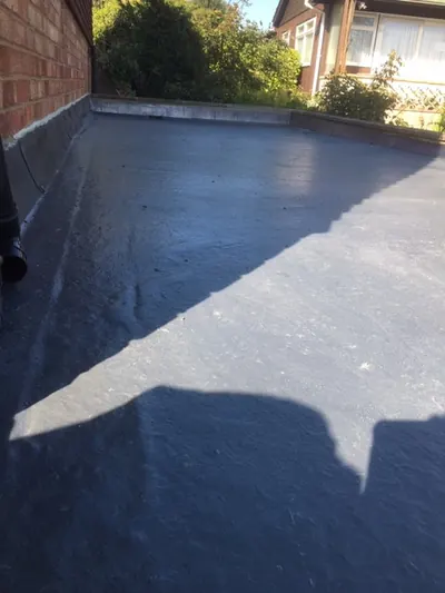 A large grey flat roof with a parapet wall, in sunlight