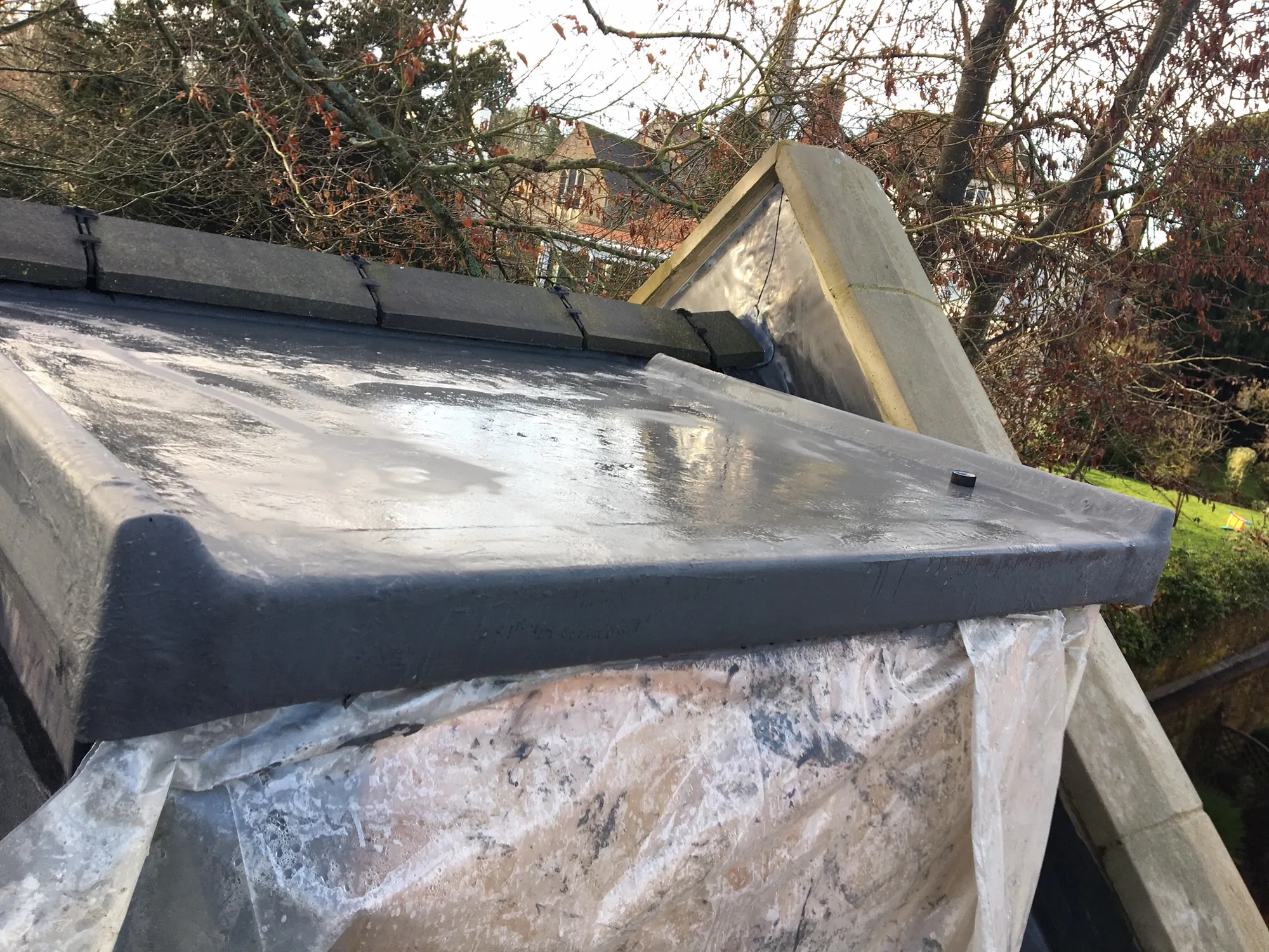 A lead-covered flat section under polythene sheeting, timber batten holding the edge