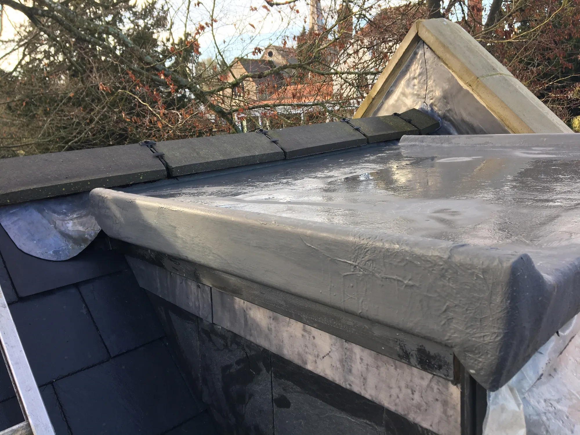 Lead dressed over a parapet coping beside a slate roof, polythene still in place