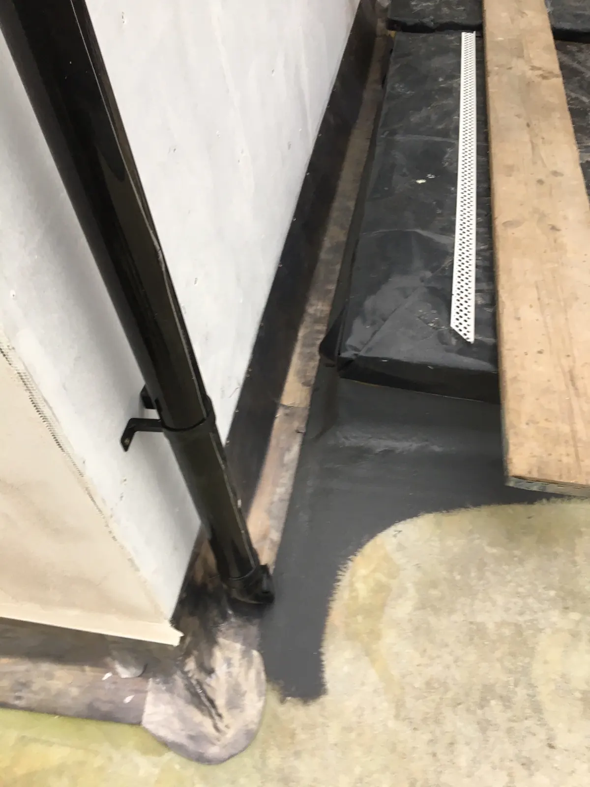 A lead gutter corner running to a downpipe outlet against a rendered wall